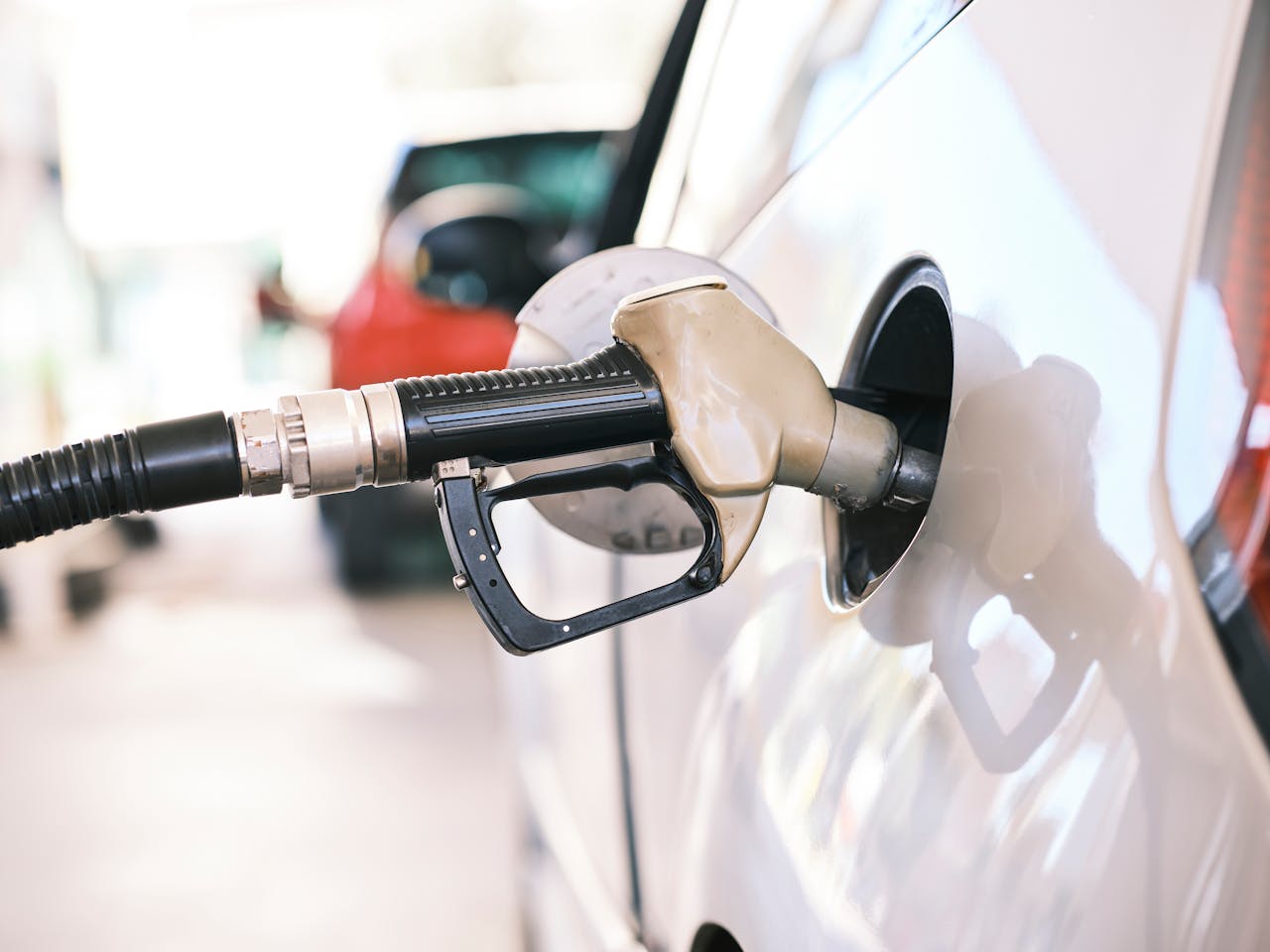 our-story Fuel nozzle inserted in car at a gas station, close-up view emphasizing energy and transportation themes.