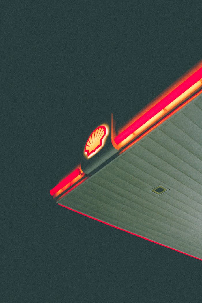 Low angle view of an illuminated gas station canopy at night, showcasing vibrant lighting in Muscat, Oman.