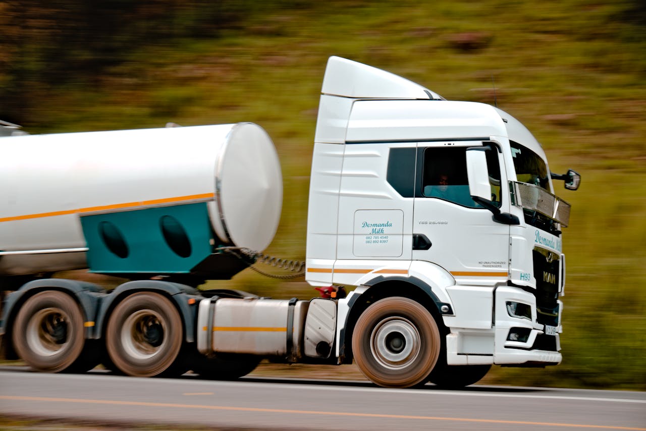 services-01 Close-up of a fast-moving white tanker truck on a highway, capturing motion and speed.