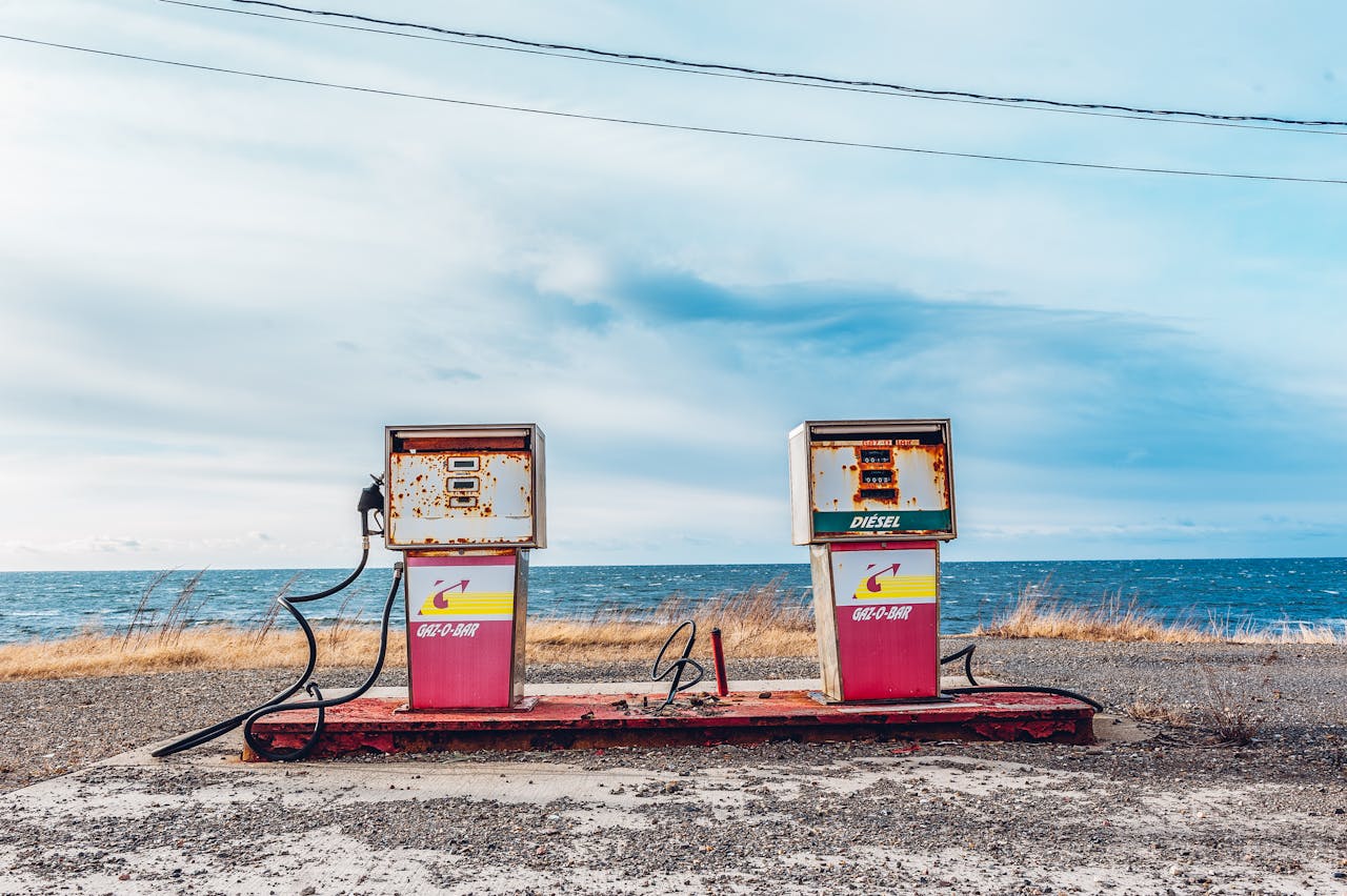 embark Vintage gas pumps on a deserted seashore with a clear sky and ocean view.