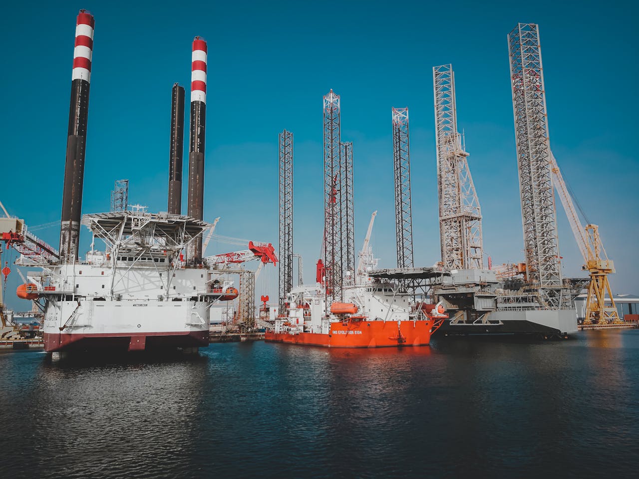 who-we-are High angle view of offshore oil platforms in Ras Laffan, Qatar under clear blue sky.